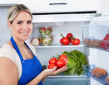 woman putting food away in her refrigerator